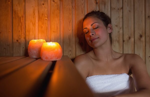 Frau entspannt in Sauna bei Kerzenlicht