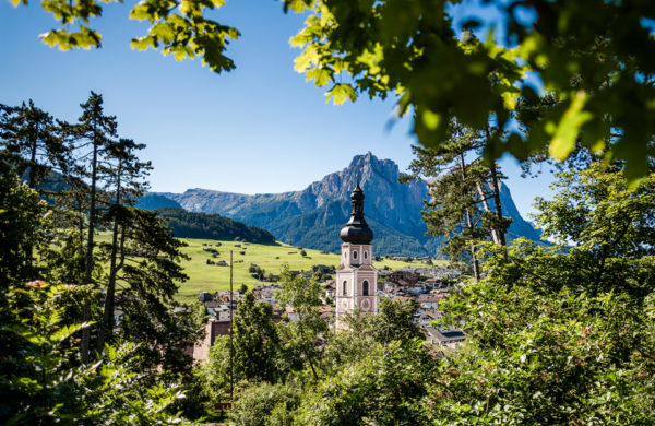 Glockenturm-in-Kastelruth-vor-malerischer-suedtiroler-Berglandschaft